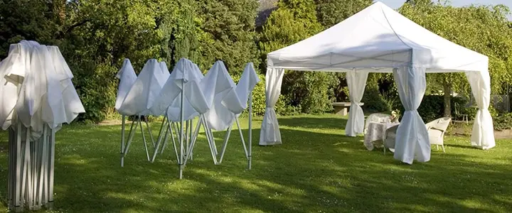 Faltpavillon PRO im Garten, teilweise aufgebaut, mit Tisch und Stühlen darunter