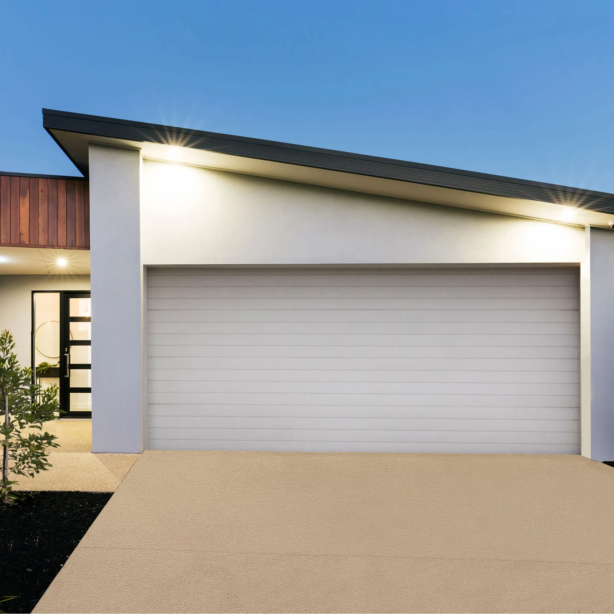 Una casa moderna con garage chiuso e ingresso illuminato al crepuscolo