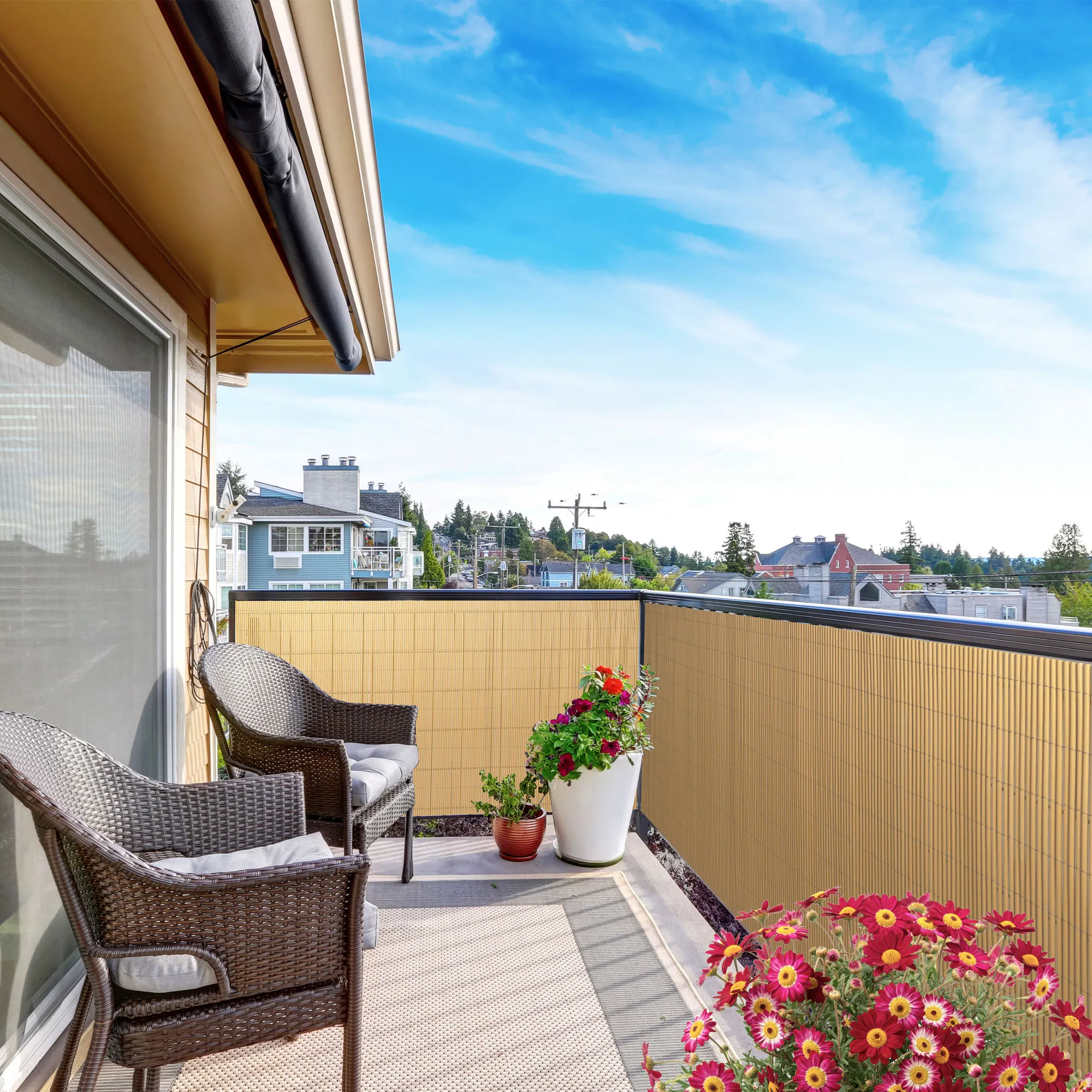 Balcone con rivestimento in bambù, due sedie e piante in vasi