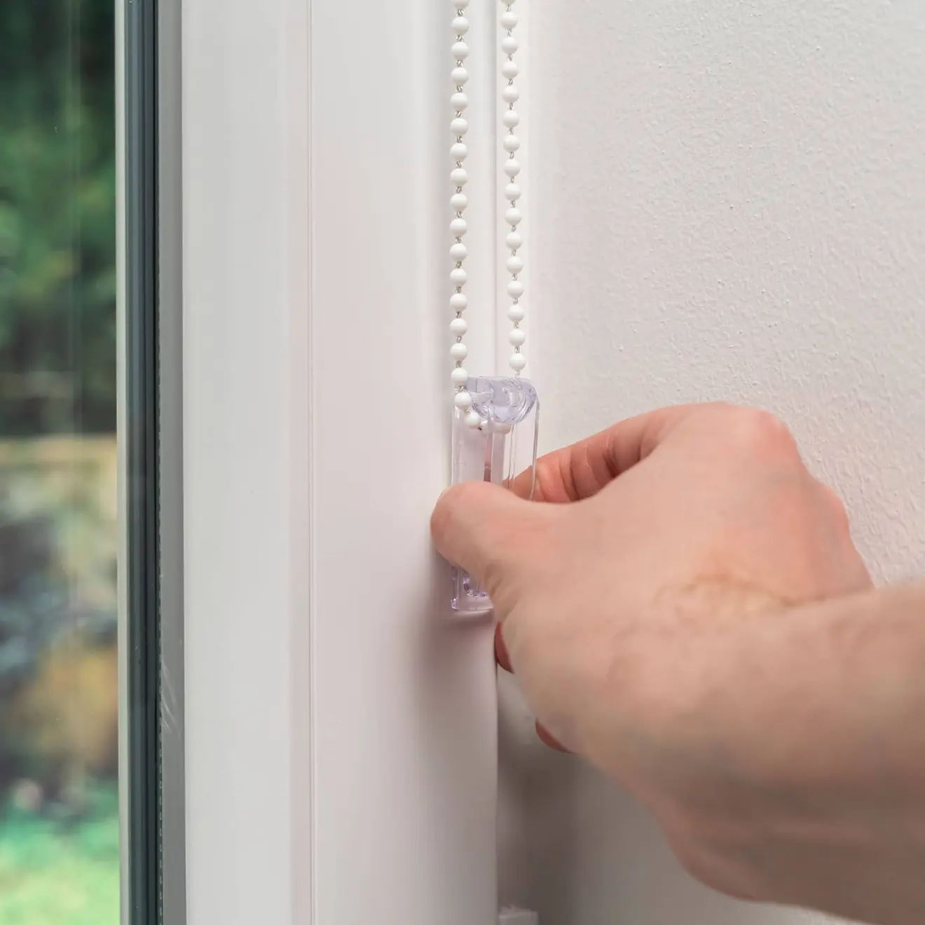 Hand bedient Kette eines Klemmfix Doppelrollos an einem Fensterrahmen