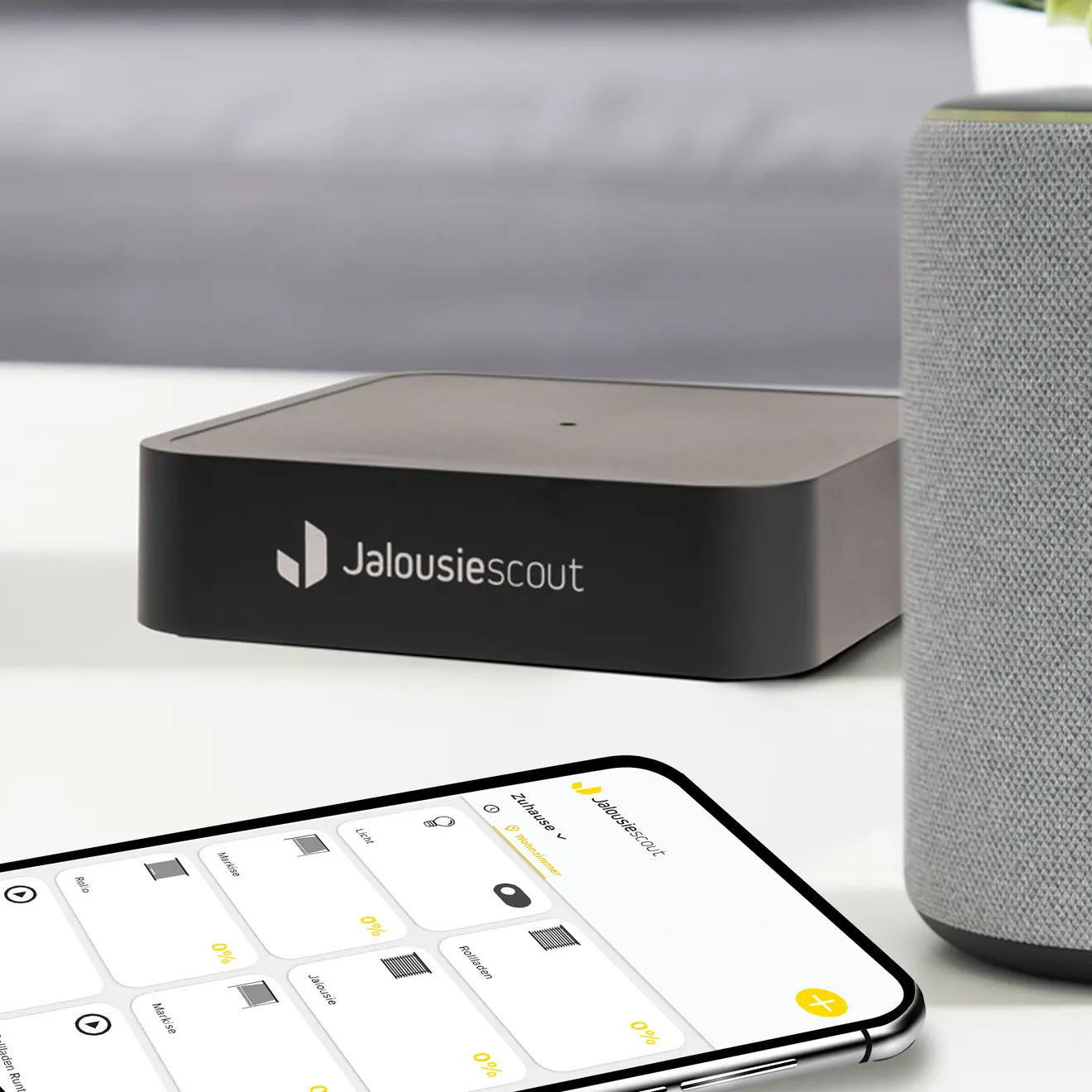 Smart-Home-Bridge auf Tisch, daneben Smartphone mit Steuerungs-App und Lautsprecher