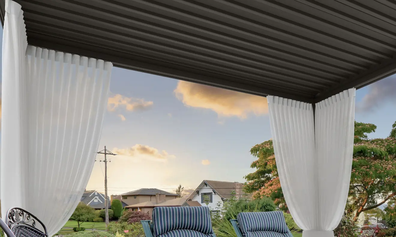 Pergola mit Vorhängen, die einen überdachten Außenbereich mit Sitzgelegenheiten umrahmen