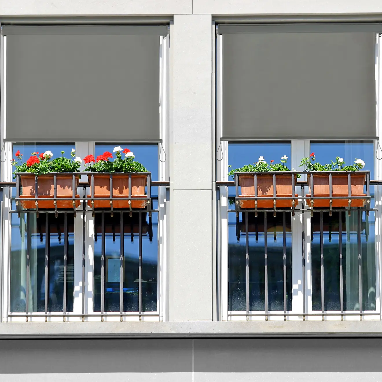 Balkon mit grauen Rollos und Blumenkästen am Geländer