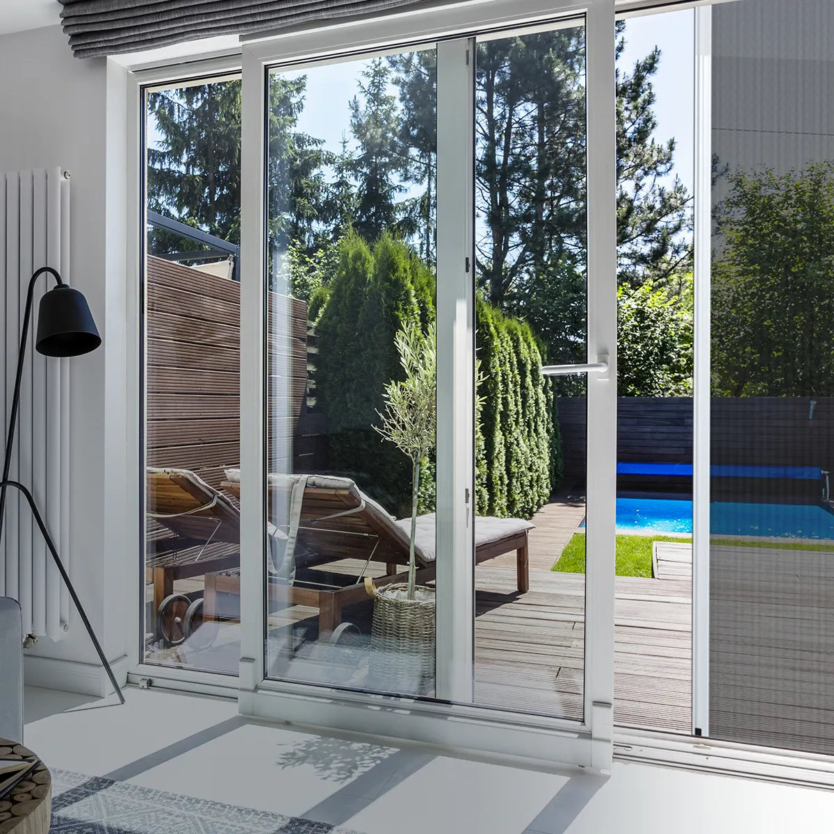 Porta scorrevole con vista su terrazza e giardino con piscina e lettini