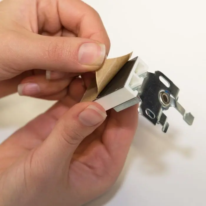 Hände halten einen Universal Haftträger mit abziehbarer Schutzfolie