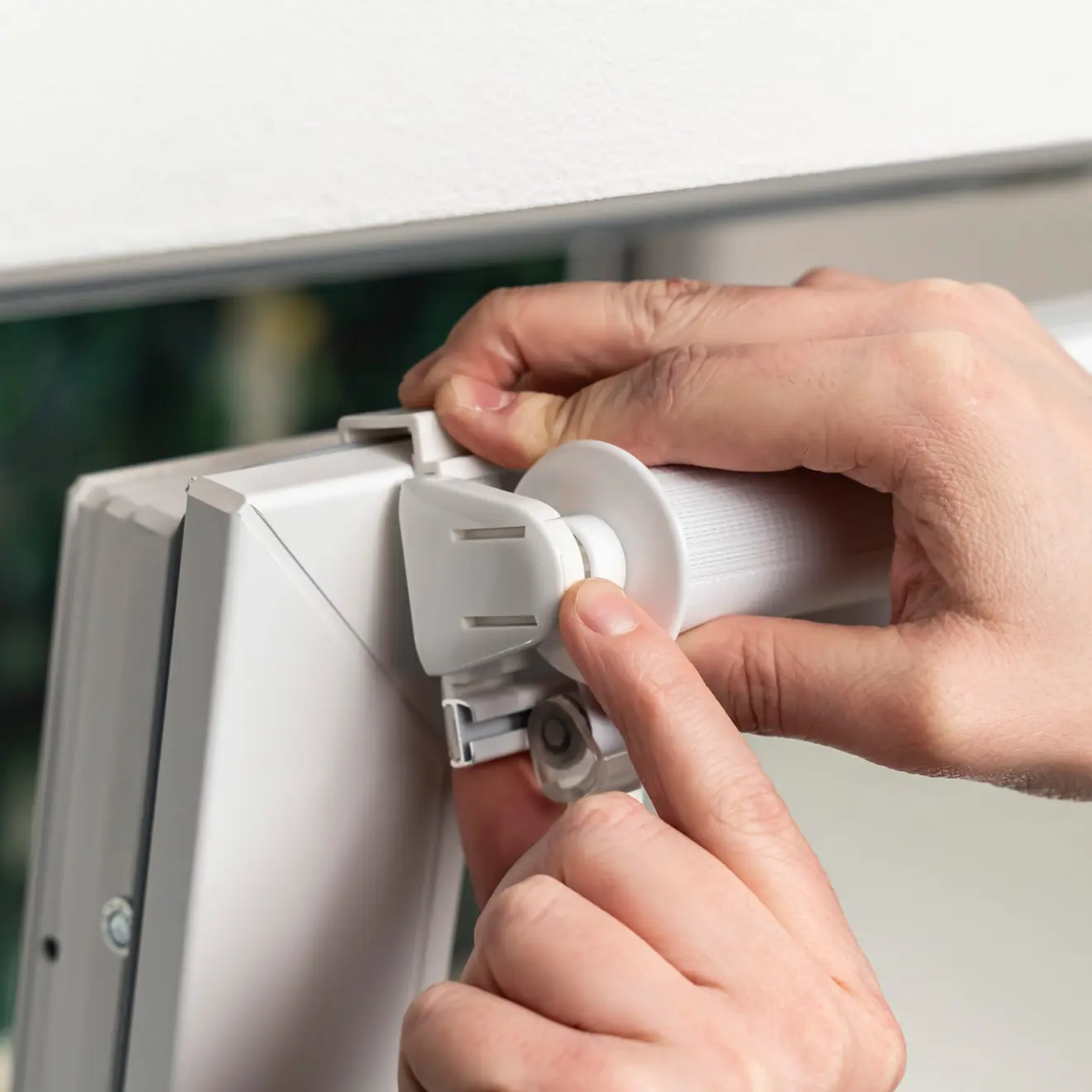 Hände montieren ein Klemmfix Doppelrollo an einem Fensterrahmen