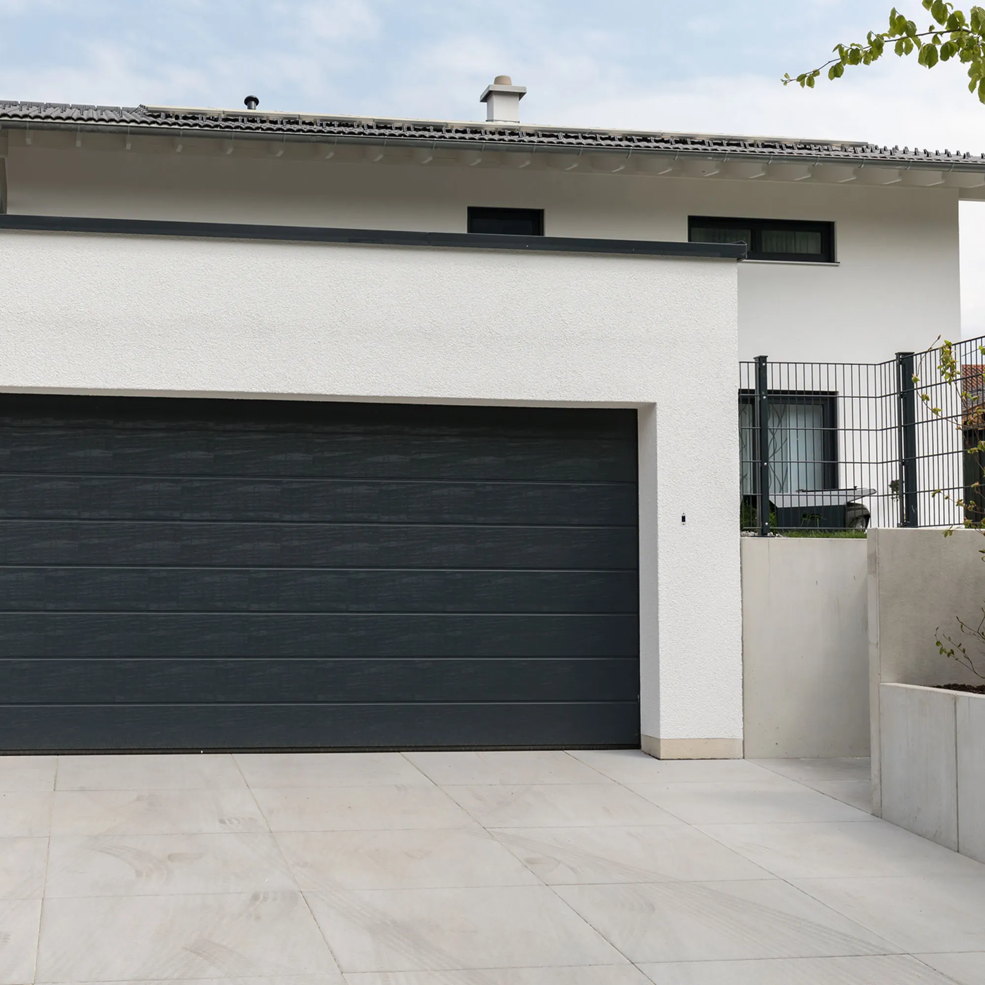 Porta del garage con casa e vialetto adiacenti, nessun pulsante a muro visibile