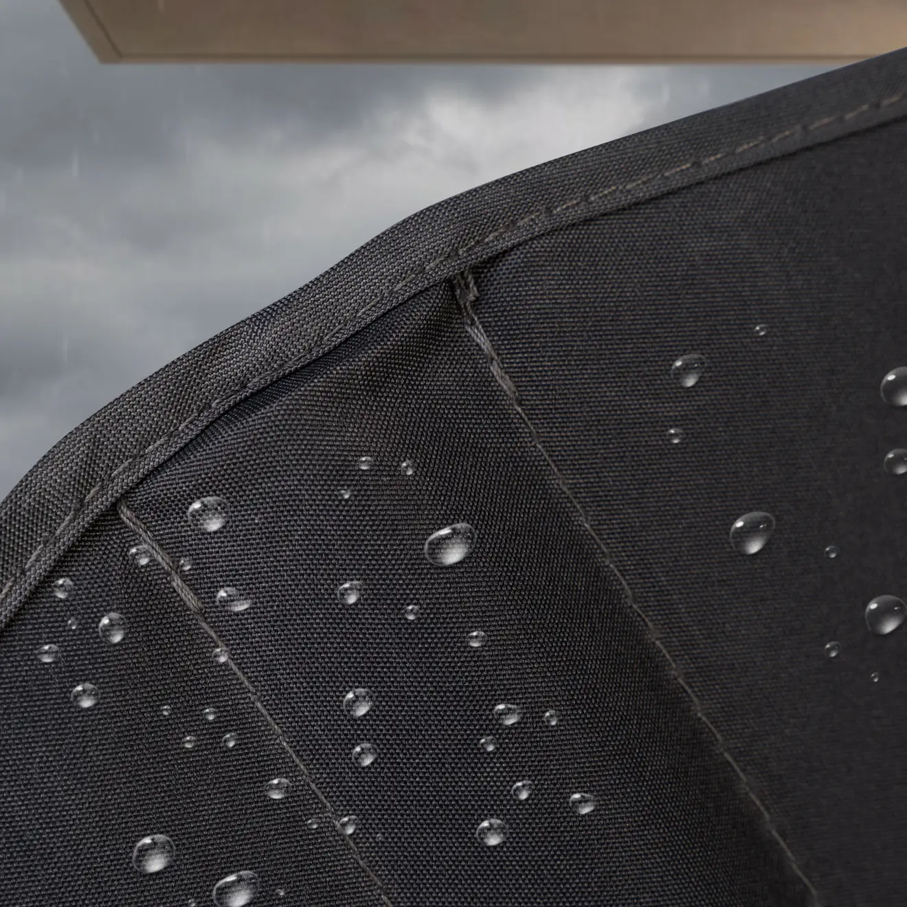 Detailansicht eines wasserabweisenden Balkonfächer-Stoffs mit sichtbaren Regentropfen auf der Oberfläche