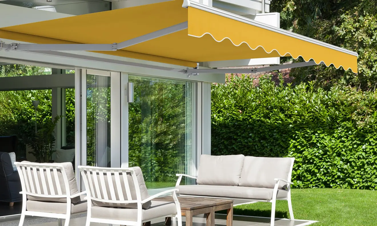 Gelenkarmmarkise Basic 2000 über Terrasse mit Sitzmöbeln und Glasfront