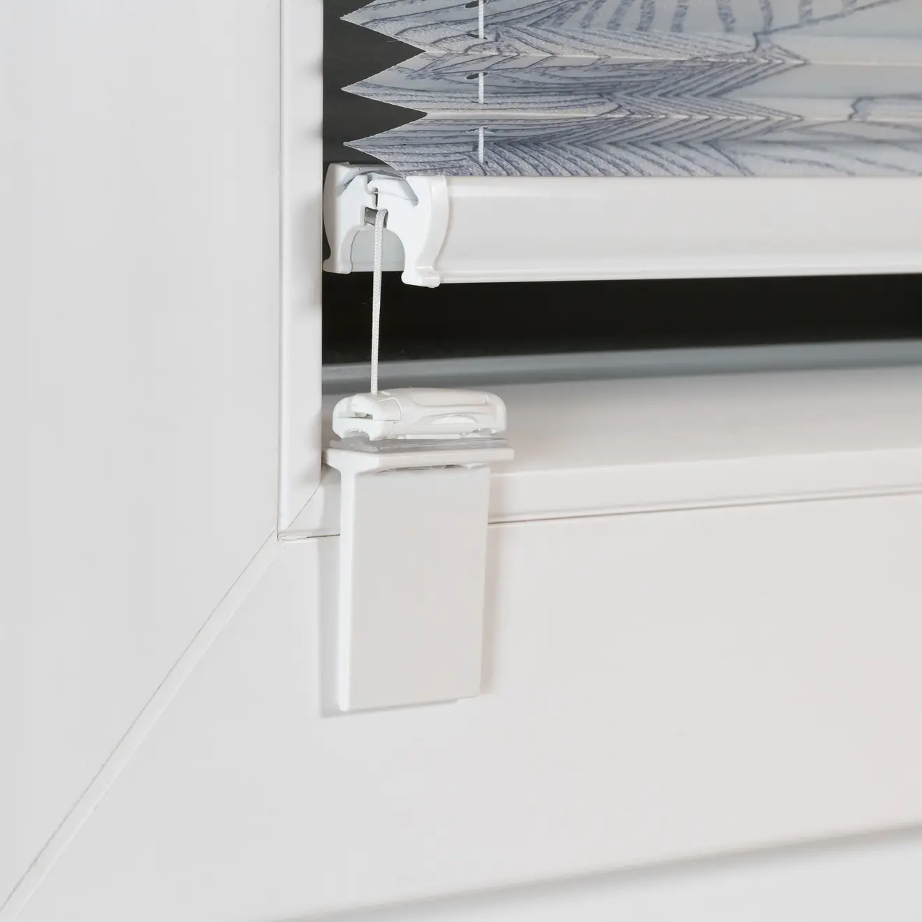 Klebehalter für Cosiflor Plissees an einem Fensterrahmen montiert