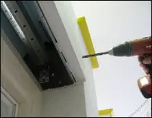 Trapano che fora un muro accanto a un telaio di finestra.