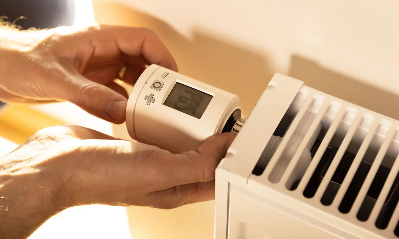 Person installiert ein smartes Heizkörper-Thermostat an einem Heizkörper