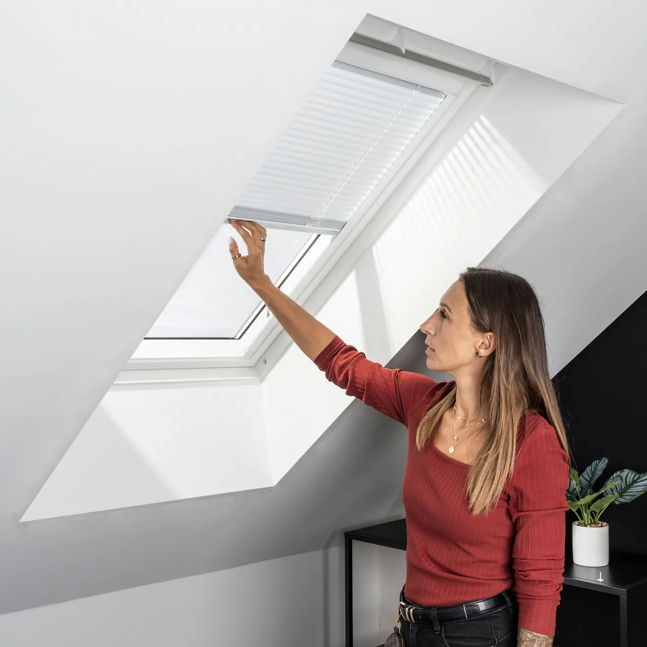 Personne ajustant un store plissé intérieur sur une fenêtre de toit