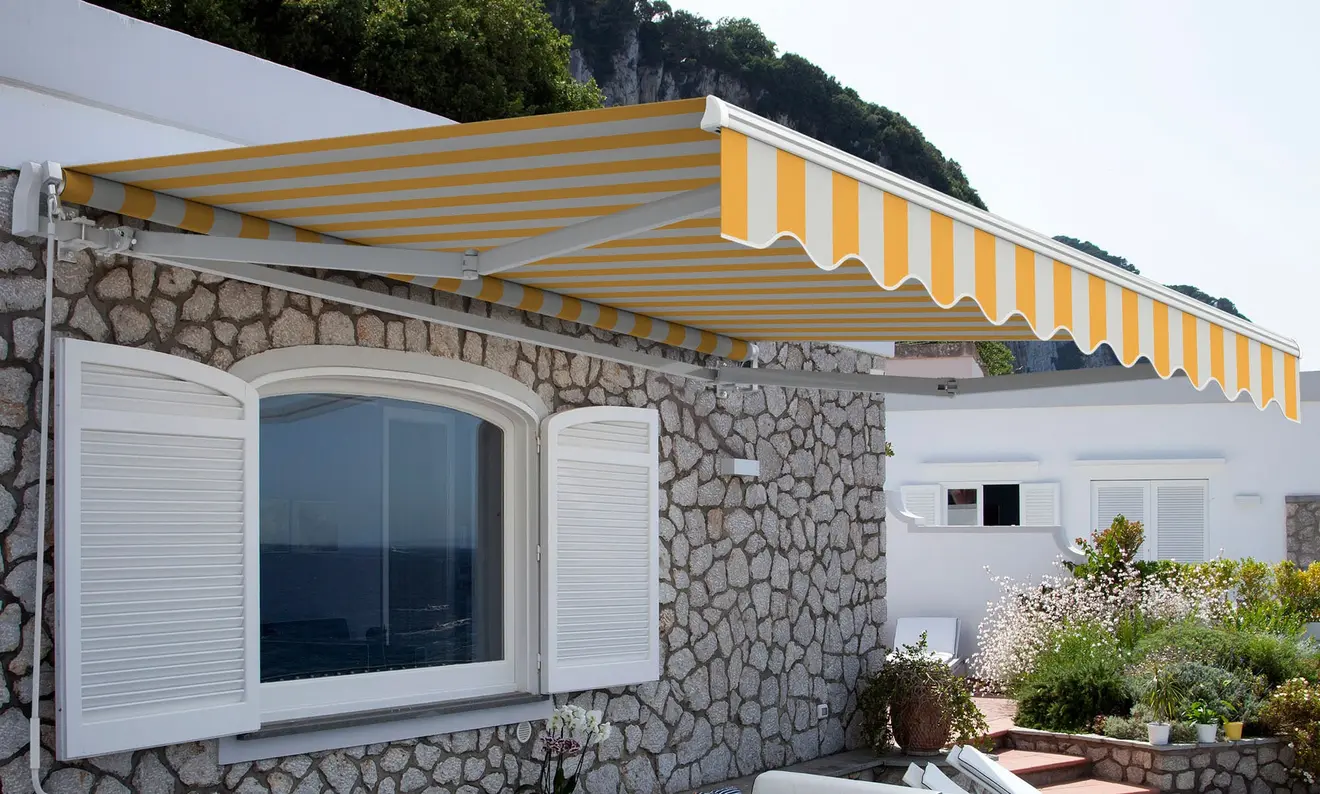 Gelenkarmmarkise mit Wand- und Deckenhalterung an einem Gebäude montiert
