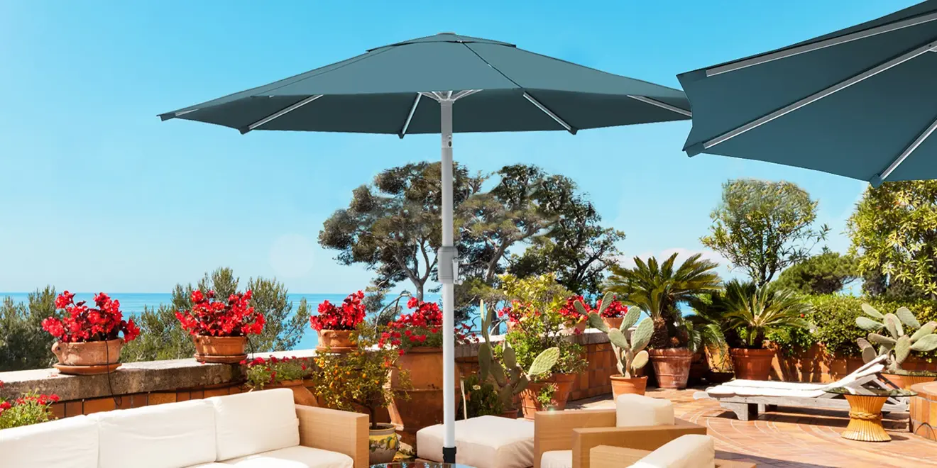 Mittelmast-Sonnenschirm auf Terrasse mit Pflanzen und Sitzmöbeln im Freien