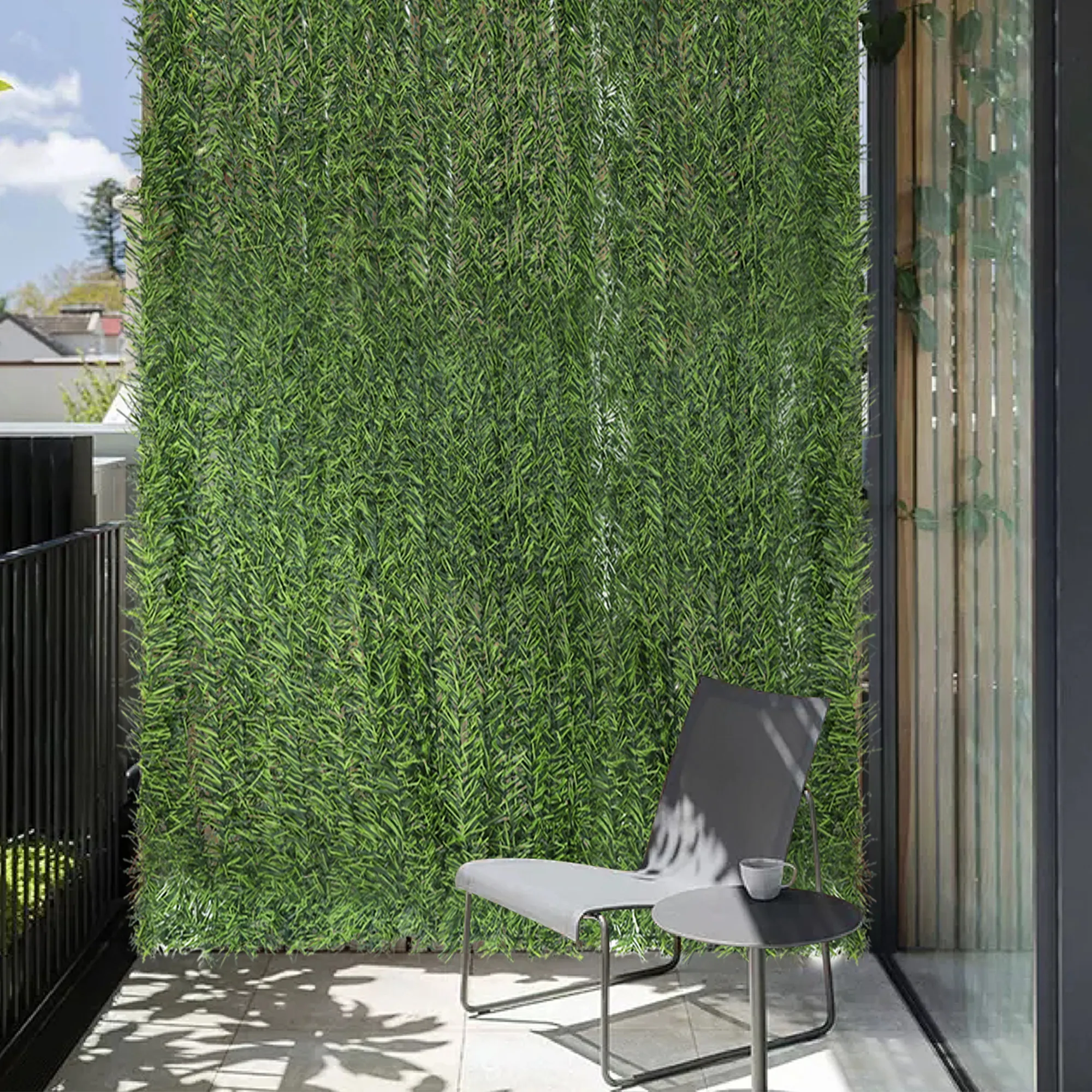 Siepe artificiale come schermo per la privacy su un balcone con sedia e tavolo