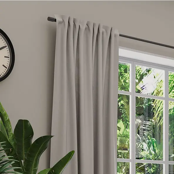 Leinenvorhang an Stange neben Fenster mit Pflanzen im Hintergrund