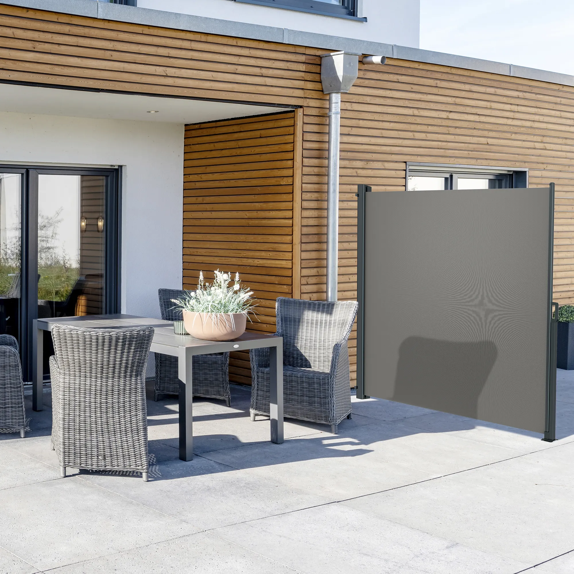 Tenda a caduta accanto a una terrazza con tavolo e sedie, offre protezione visiva e dal vento