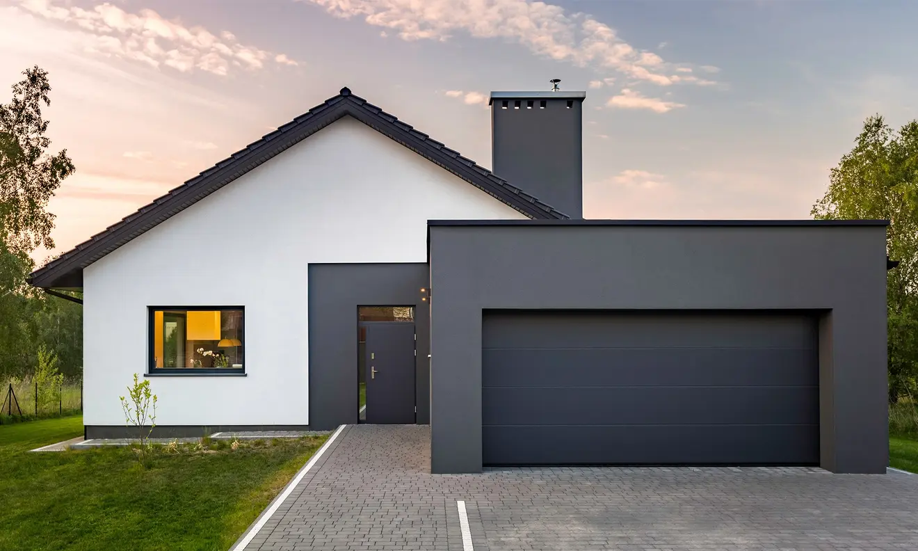 Modernes Haus mit integriertem Garagentor, Einfahrt und umgebender Natur