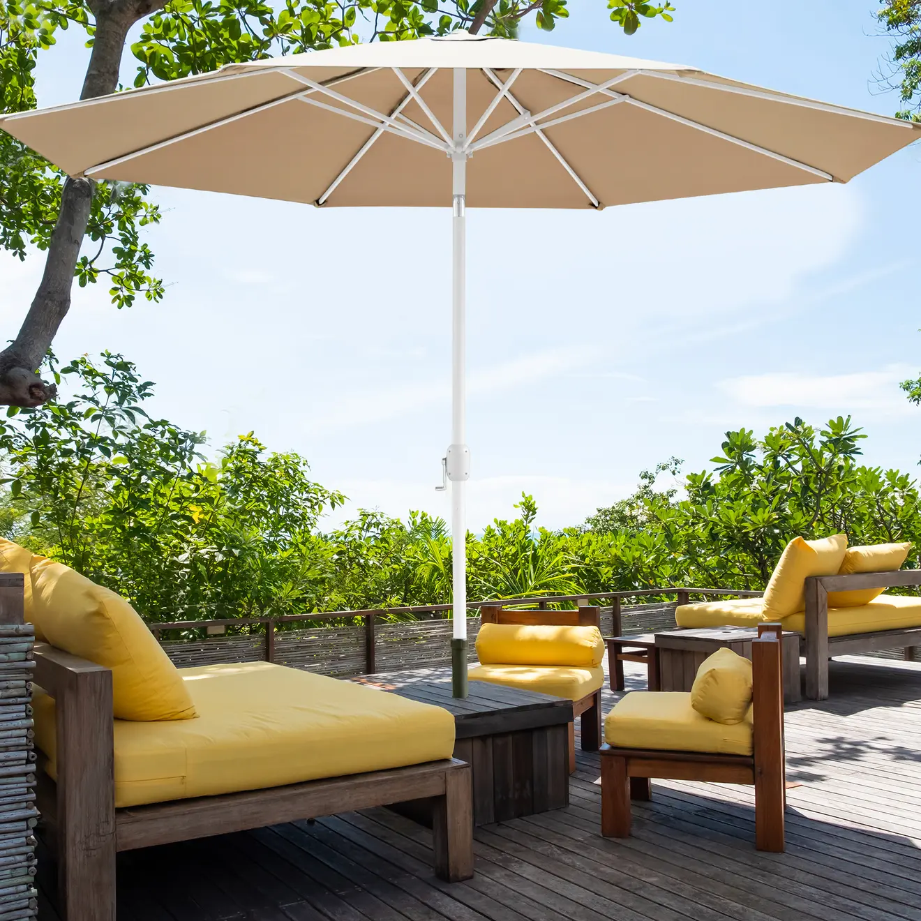 Großer Sonnenschirm über Sitzgruppe auf Terrasse mit grüner Gartenumgebung