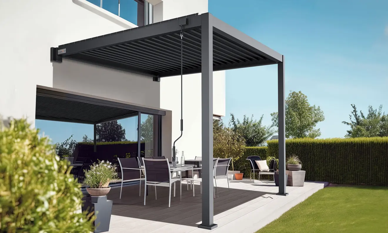 Pergola mit Lamellendach über einer Terrasse mit Gartenmöbeln und Pflanzen