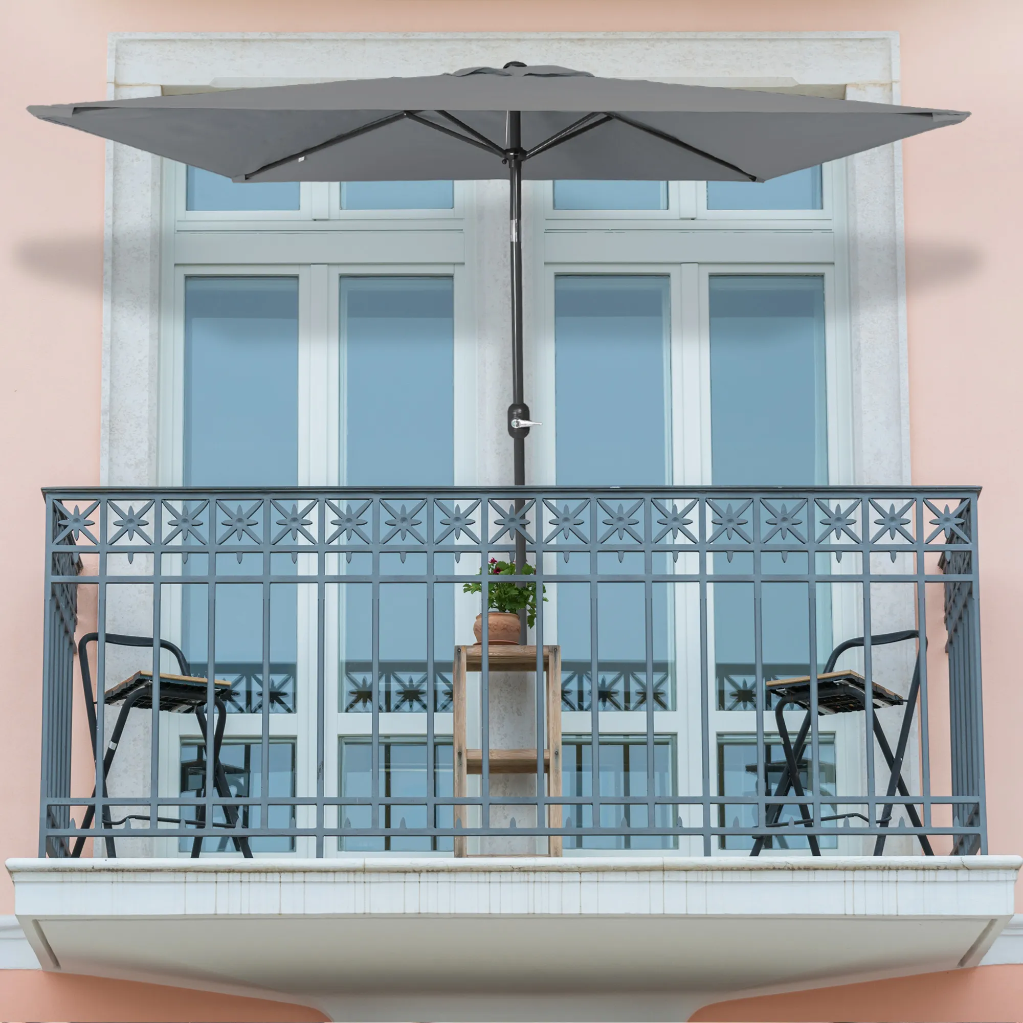 Piccolo ombrellone pieghevole su un balcone sopra un tavolo e sedie