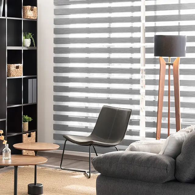 Wohnzimmer mit Doppelrollos, Sessel, Stehlampe, Regal und Couchtisch