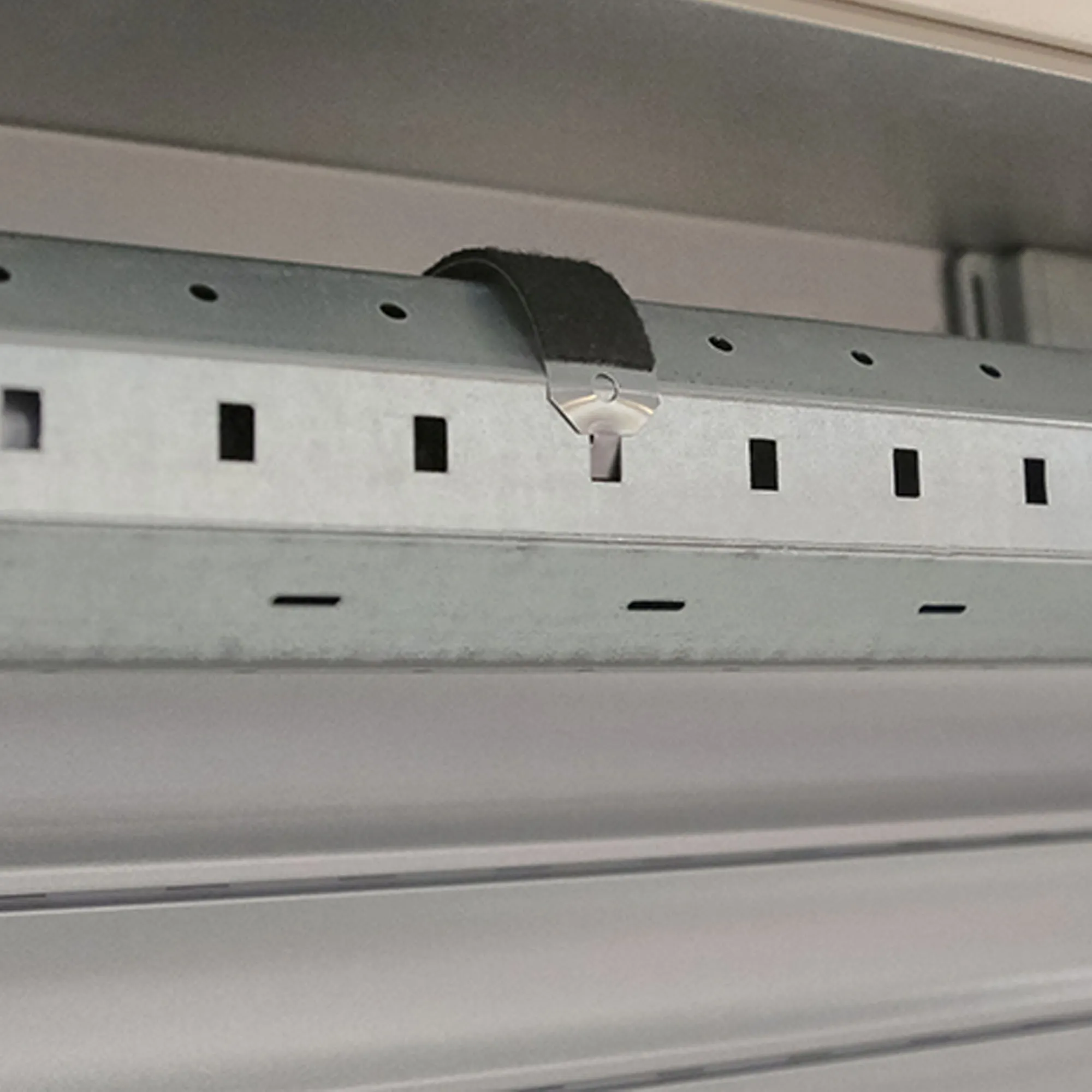 Gancio per nastro in acciaio con molla di sicurezza e protezione antigraffio fissato a una struttura metallica