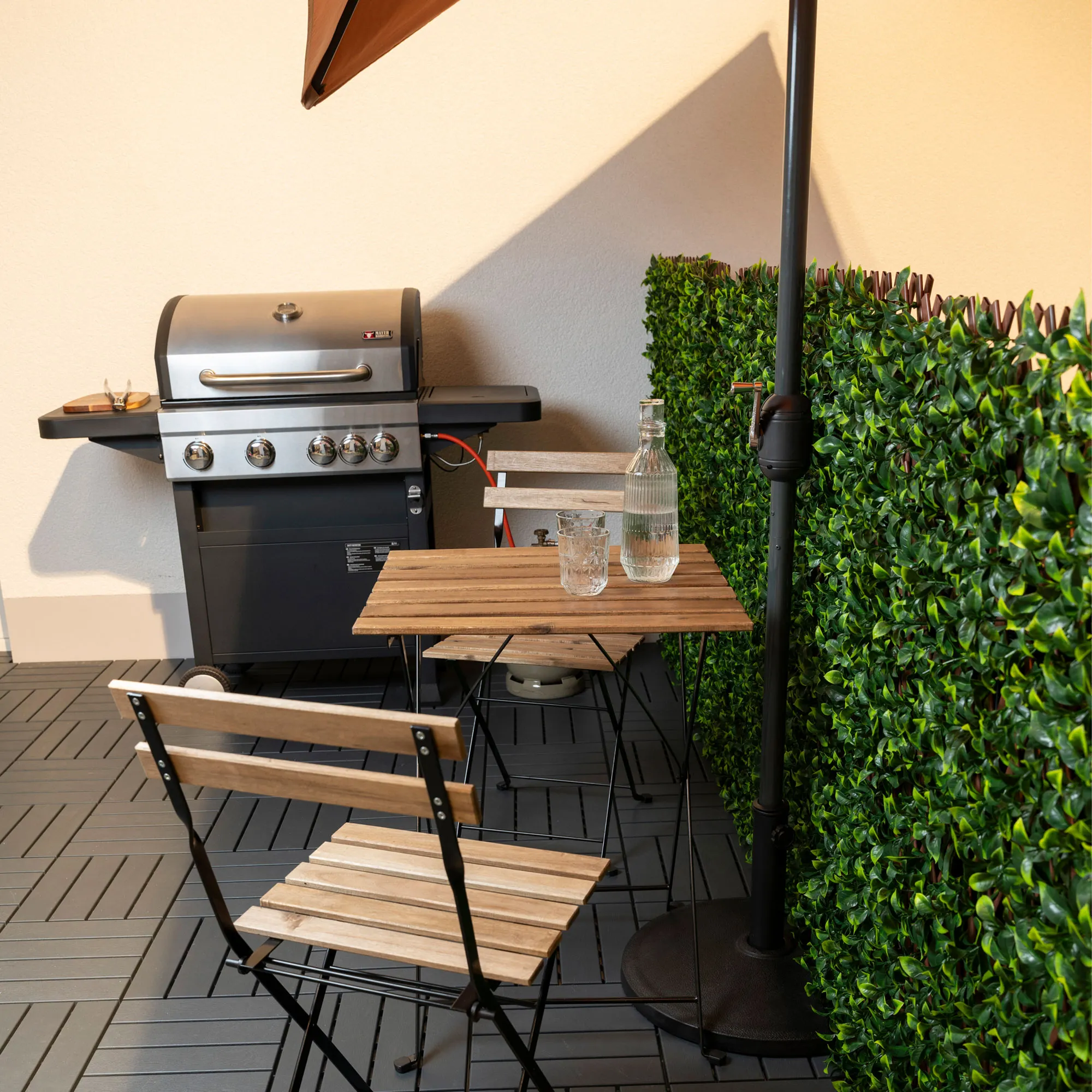 Supporto per ombrellone a forma semicircolare accanto a tavolo e barbecue su terrazza con parete de protezione