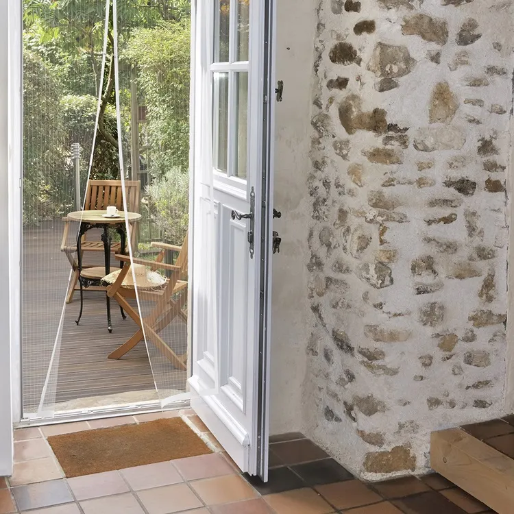 Tenda a rete magnetica su una porta aperta, vista su una terrazza con tavolo e sedie