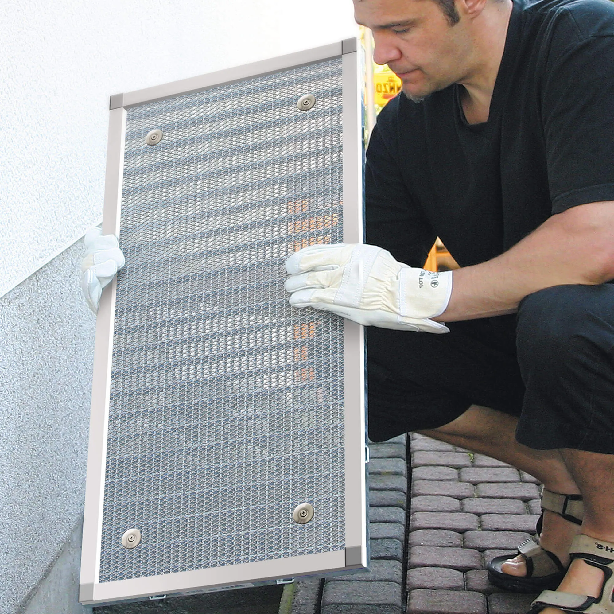 Persona monta una copertura di pozzetto con telaio in alluminio su un'apertura nel muro