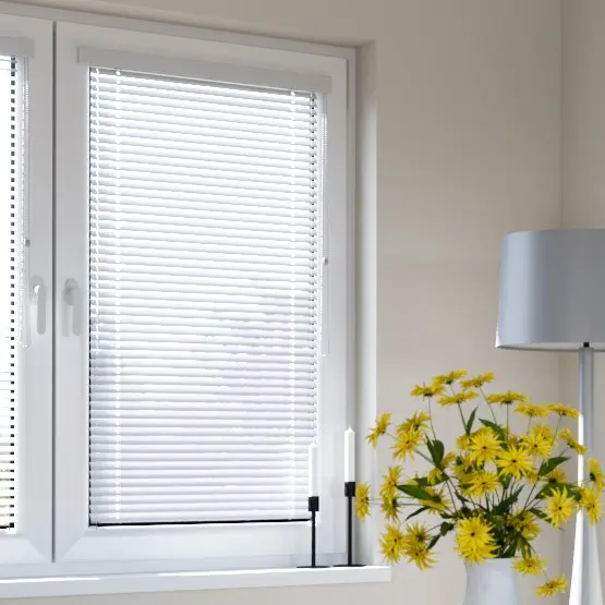 Fenster mit Jalousien, daneben eine Vase mit Blumen und eine Stehlampe