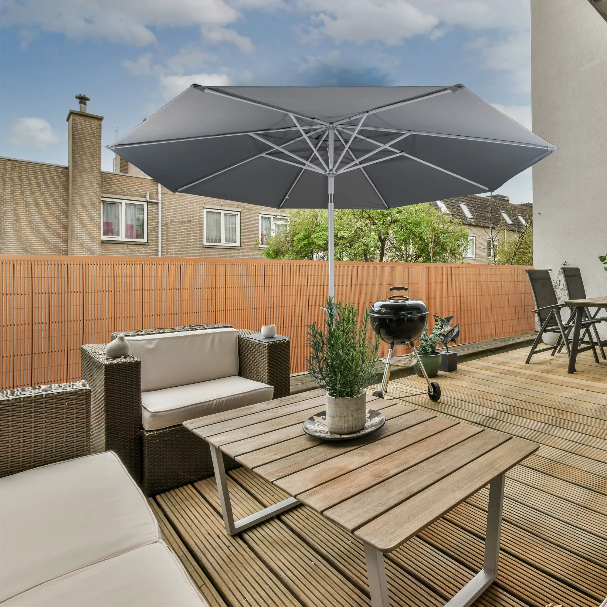 Terrazza con tappeto per la privacy in bambù, mobili da giardino e ombrellone