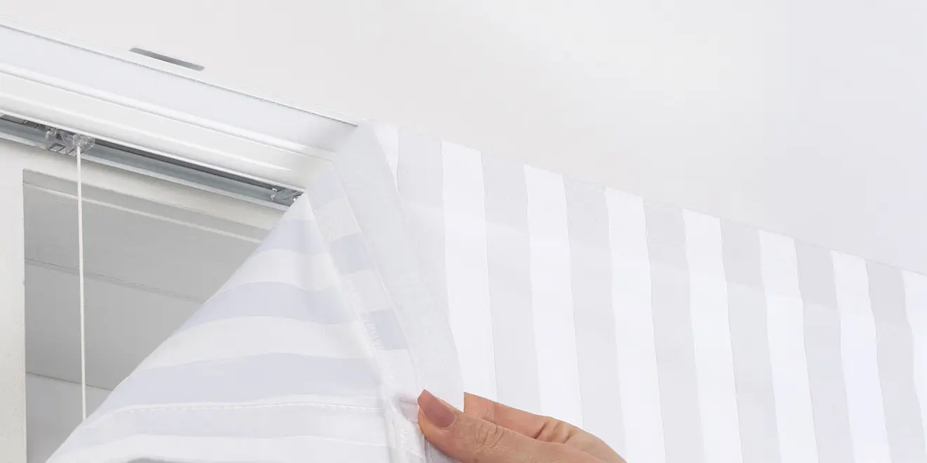 Hand befestigt Stoffbahn mit Klettverschluss an einer Schiene