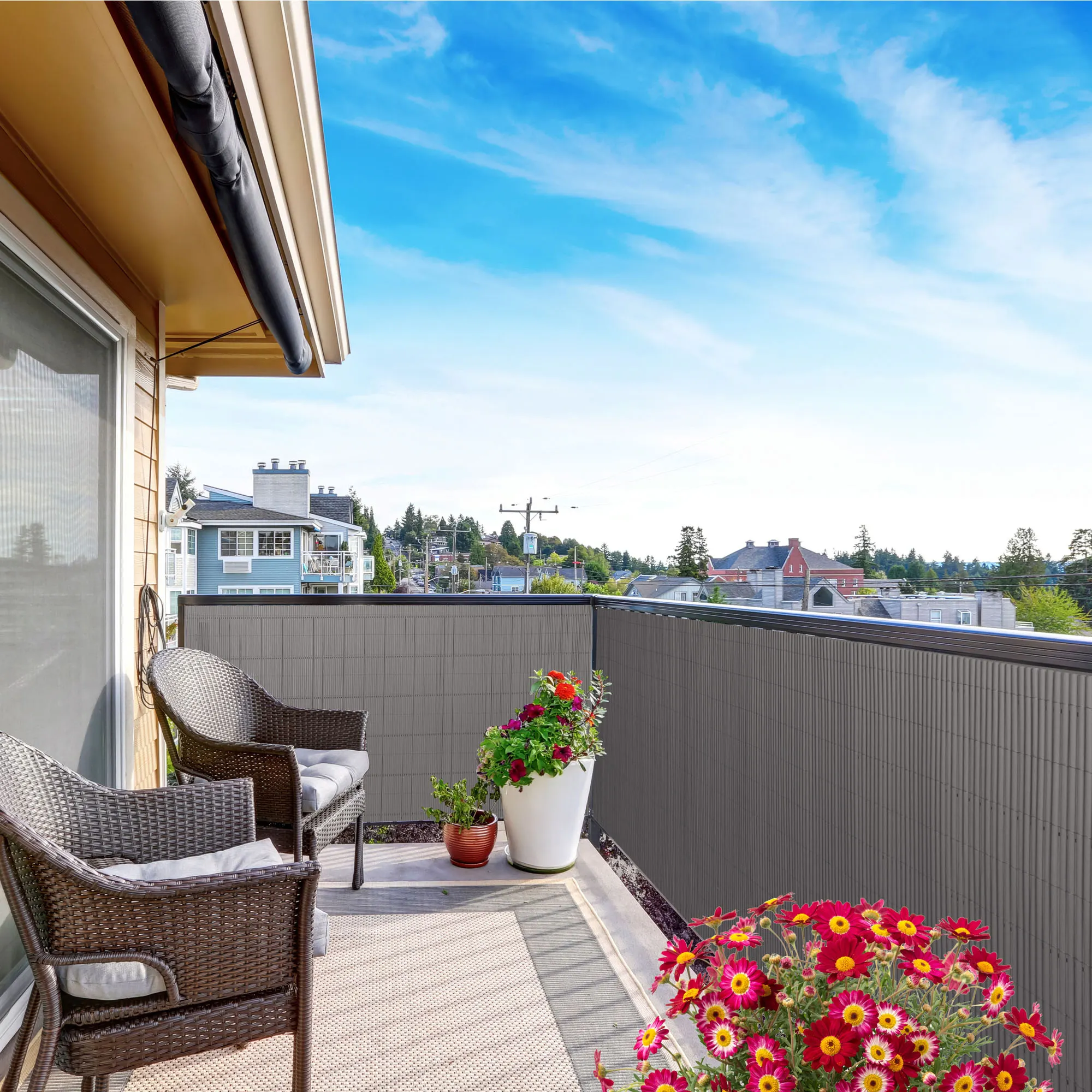 Balcone con rivestimento in bambù, due sedie e piante in vasi