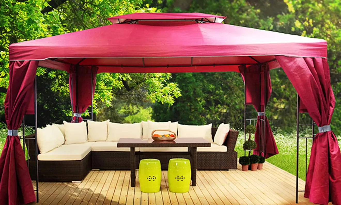 Gartenpavillon mit Vorhängen, darunter Sitzgruppe und Tisch auf Holzterrasse im Freien