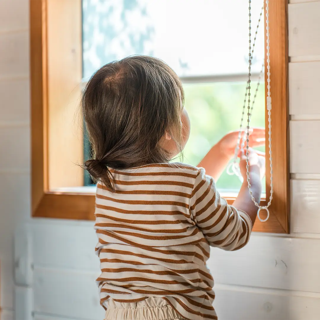 Kleinkind lernt wie es das Rollo runterlässt.