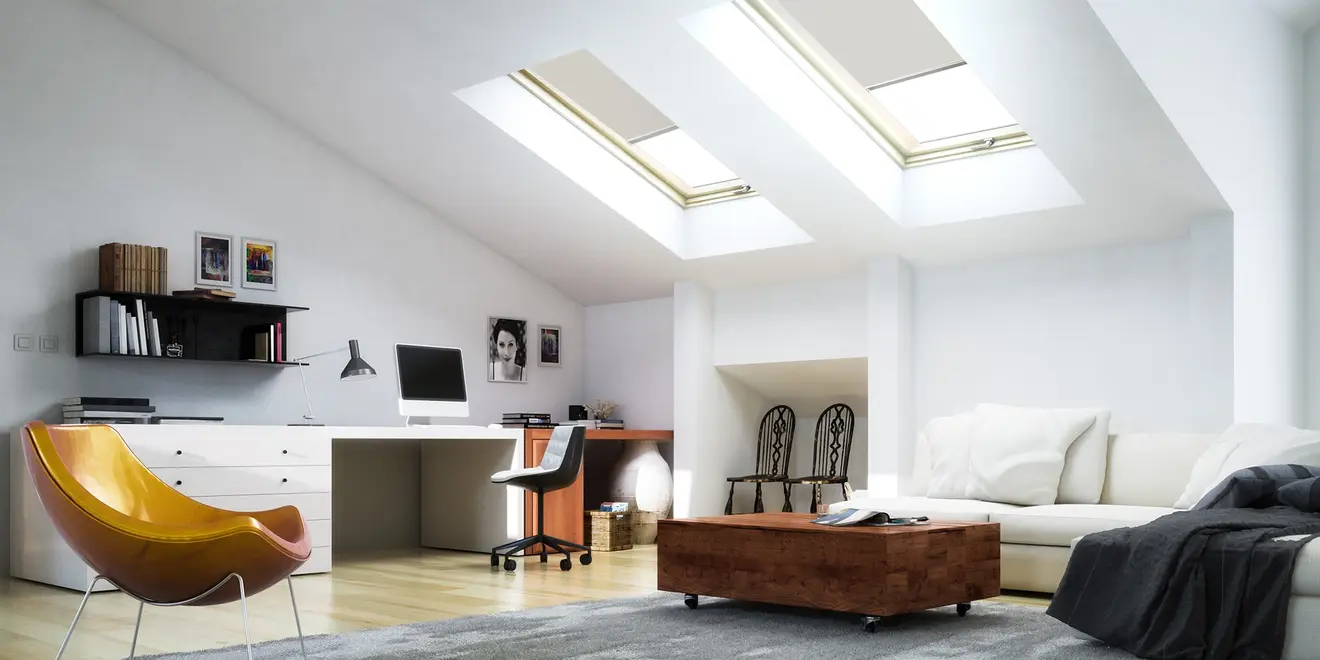 Wohnraum mit Schreibtisch, Sofa und Dachfenstern, die natürliches Licht hereinlassen