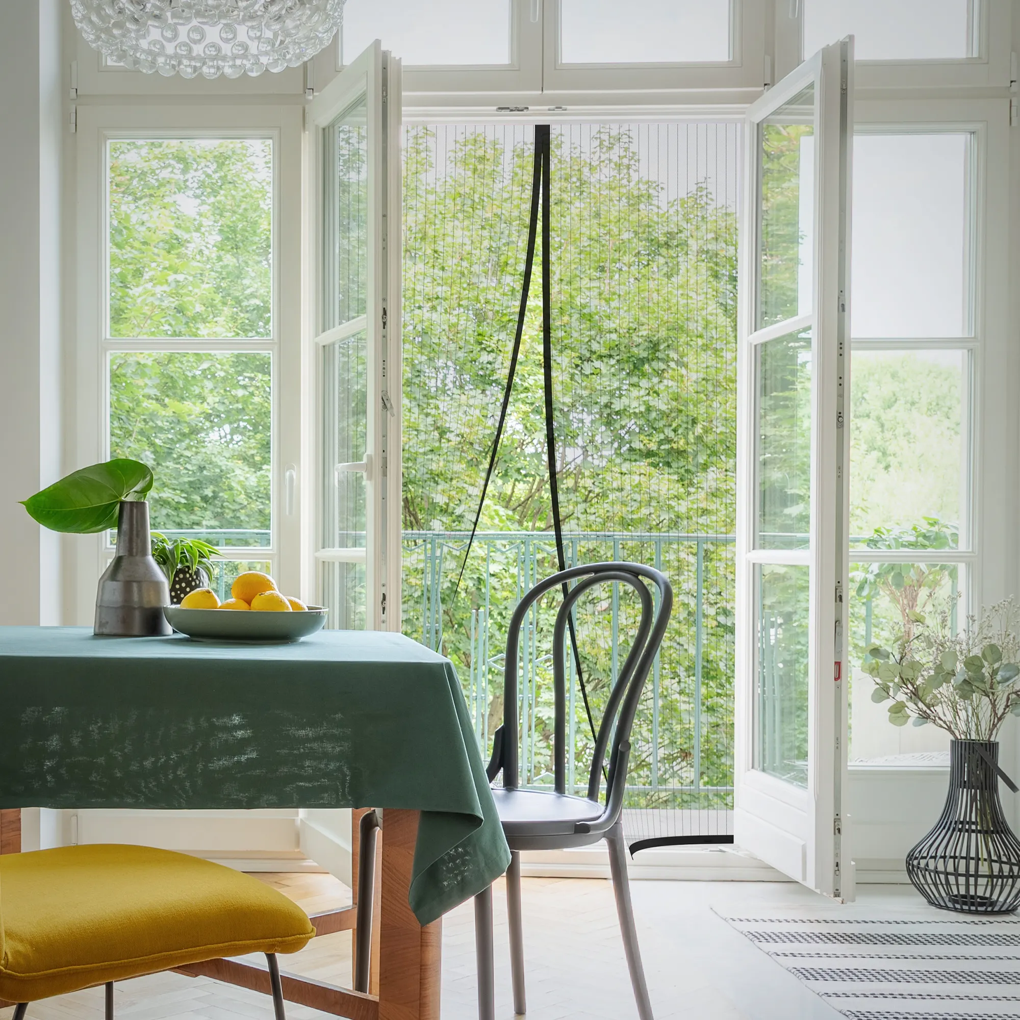 Tenda a rete magnetica su una porta aperta in un soggiorno con tavolo e sedia