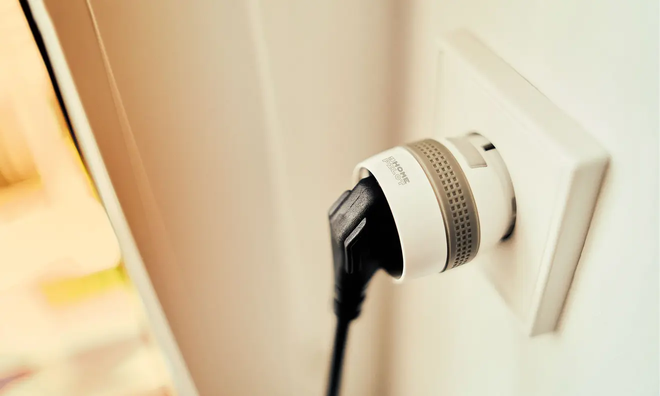 Smart-Zwischenstecker in Steckdose mit eingestecktem Kabel, seitliche Ansicht