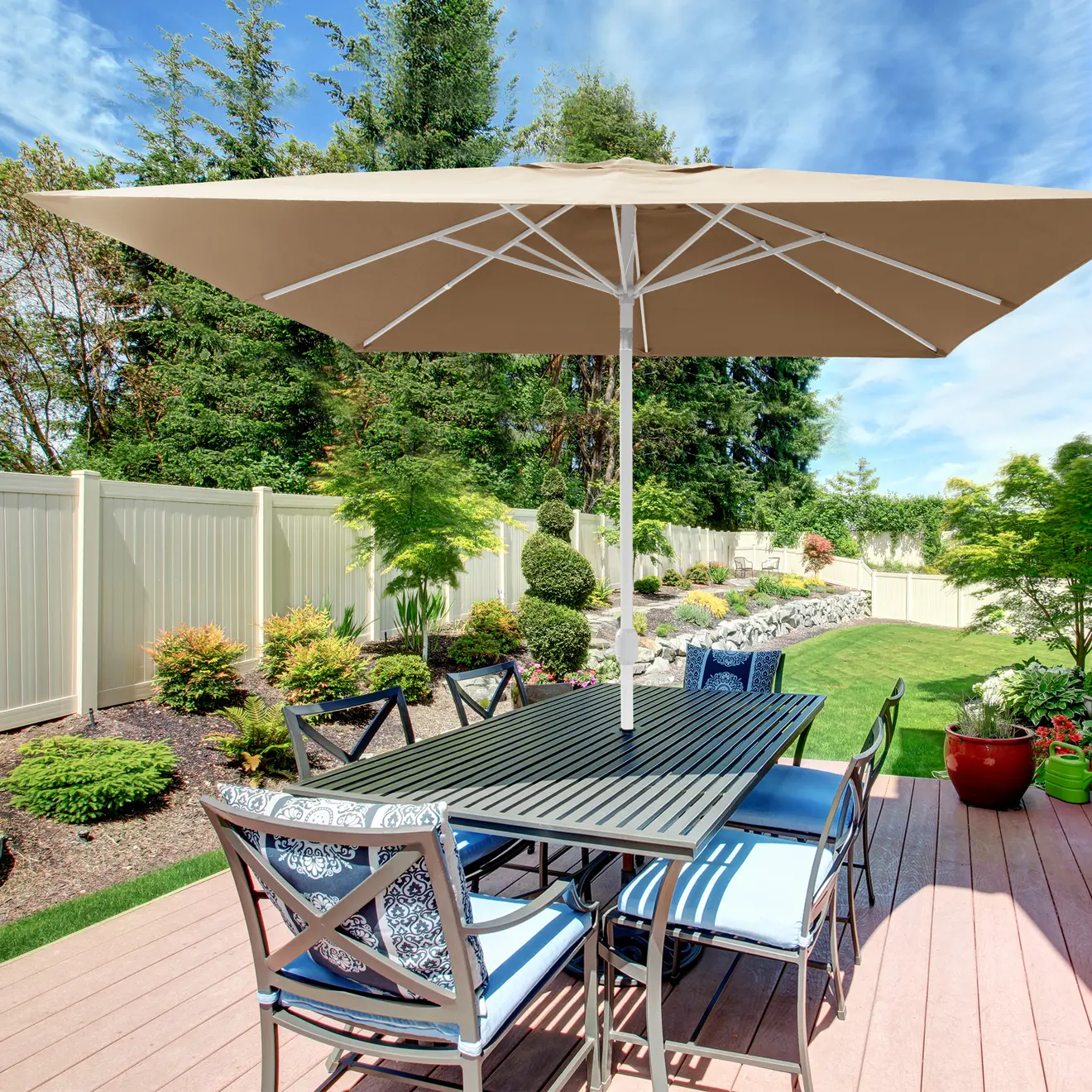 Großer Sonnenschirm über Gartentisch mit Stühlen auf Terrasse im Garten