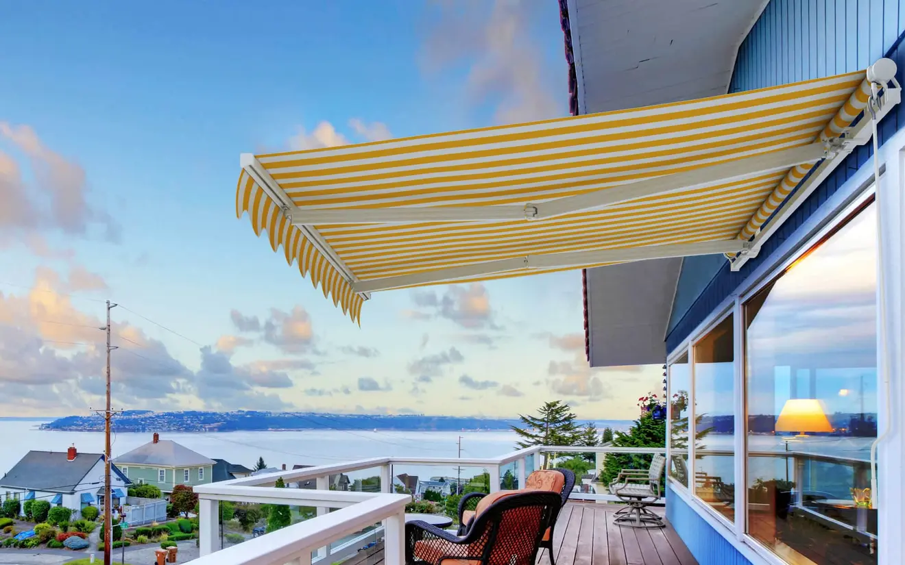 Gelenkarmmarkise auf Terrasse mit Meerblick im Hintergrund