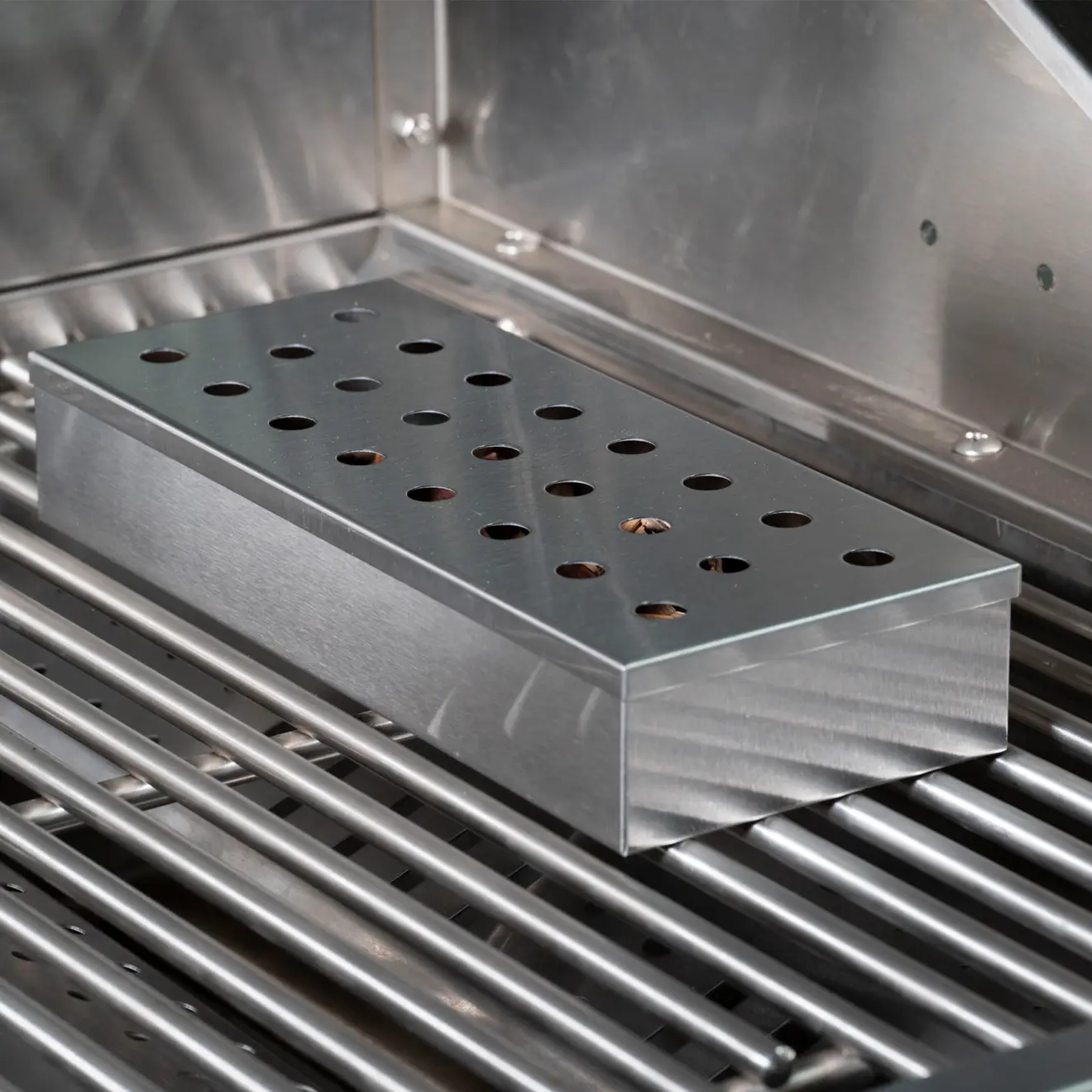 viereckige Räucherbox aus Edelstahl auf einem Grillrost