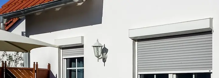 Hausfassade mit geschlossenen Rollläden und einer Außenleuchte