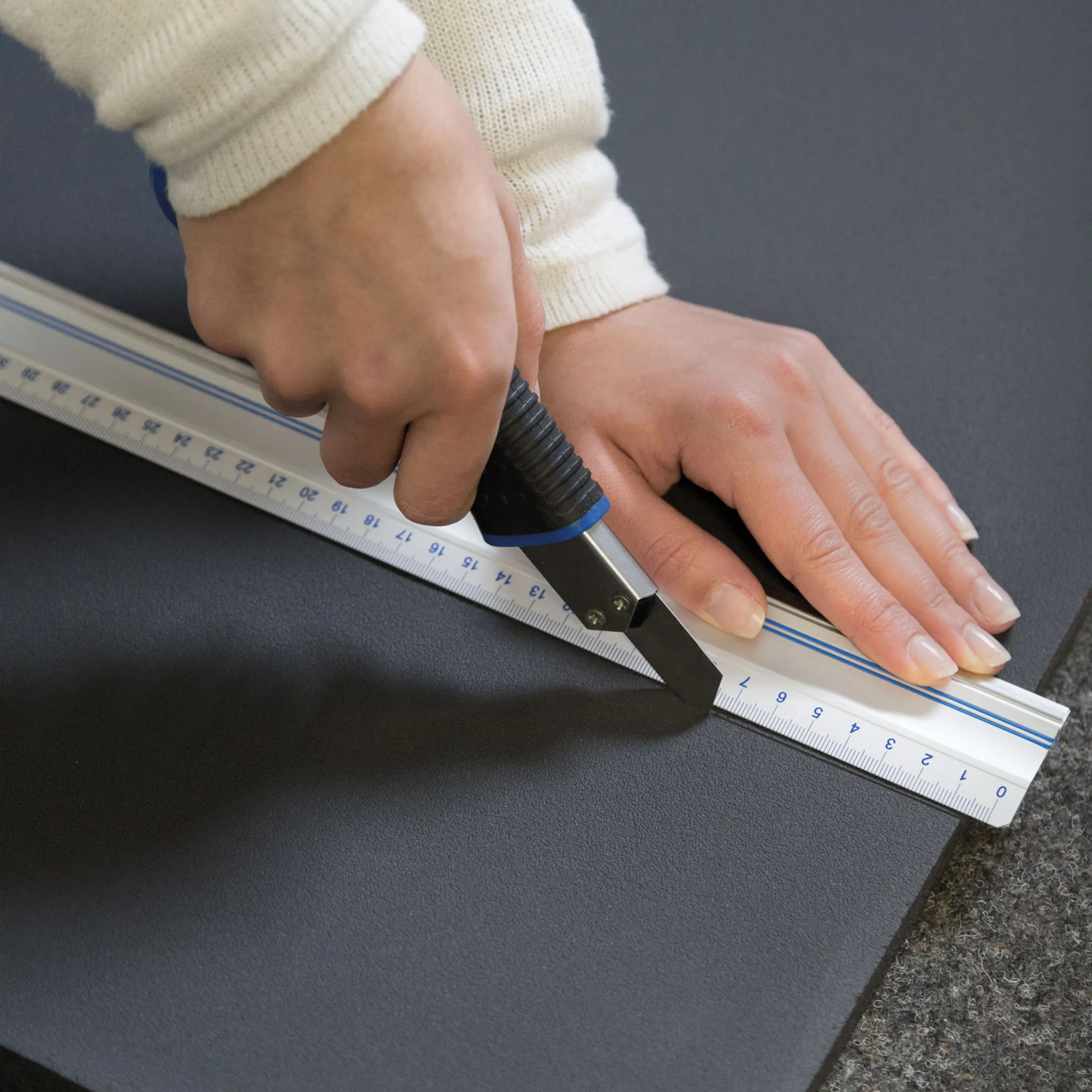 Persona che taglia un materassino isolante con un cutter e un righello