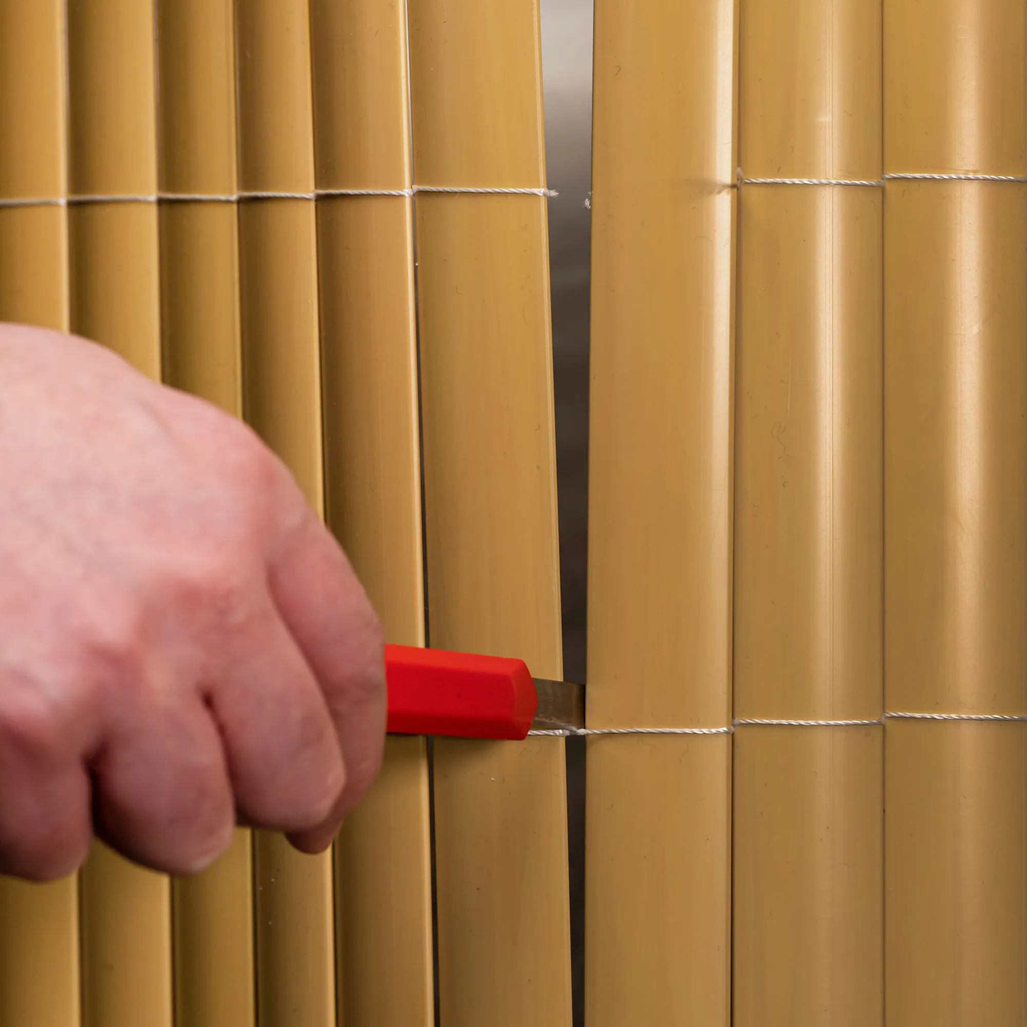 Mano che taglia un pannello di protezione in PVC con un coltello