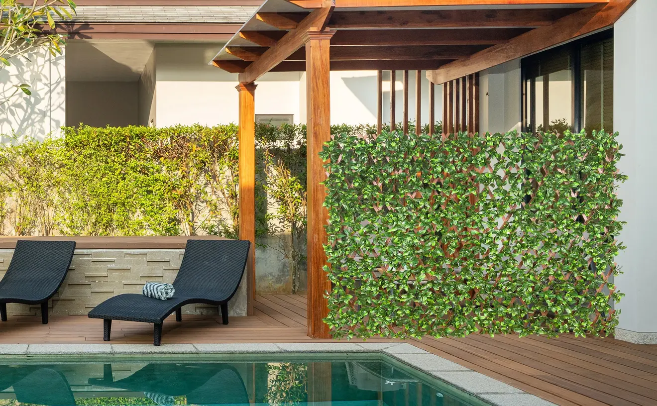 Künstliche Pflanzenwand mit Gardenienblättern an einer Terrasse neben einem Pool