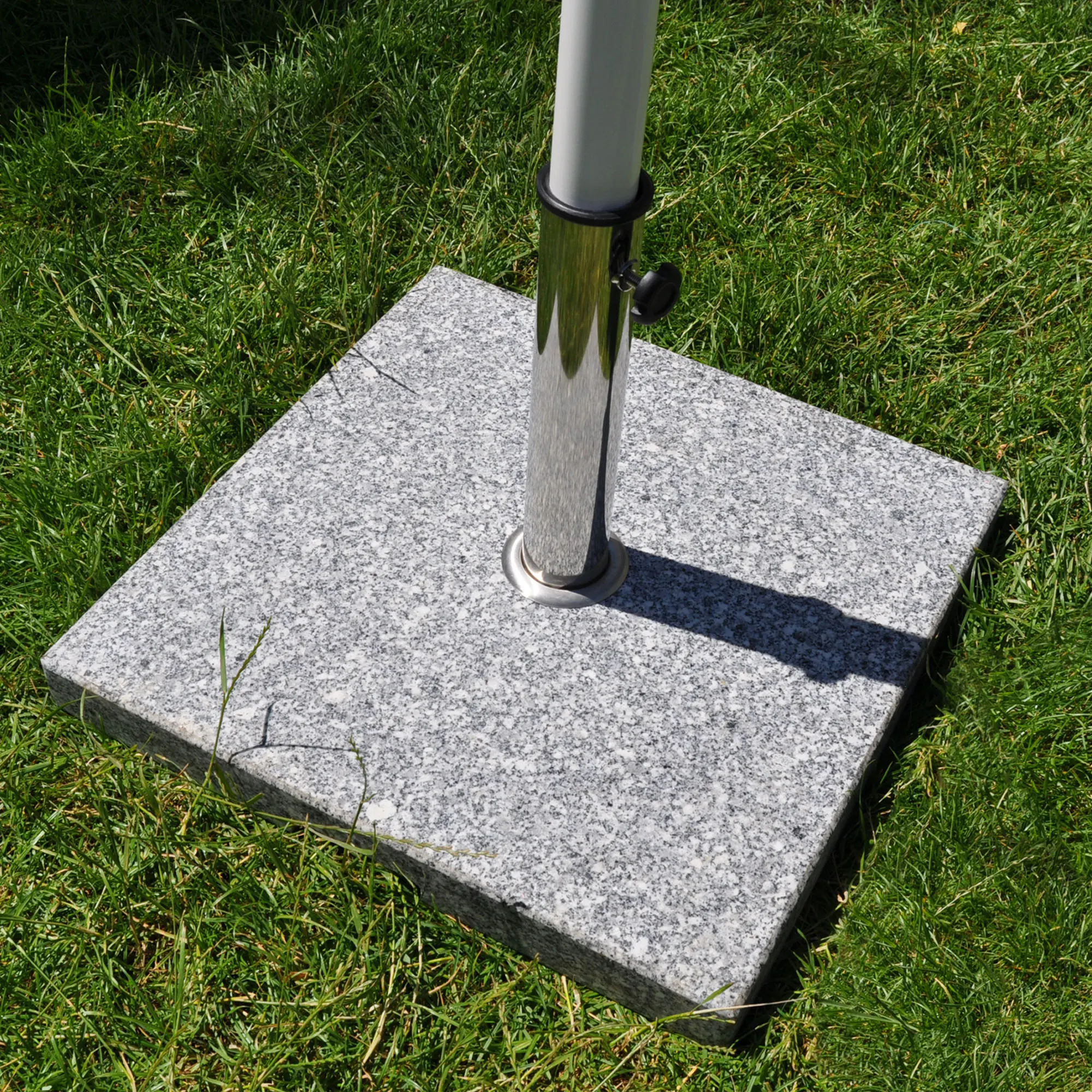 Base quadrata in granito su prato con tubo per ombrellone inserito