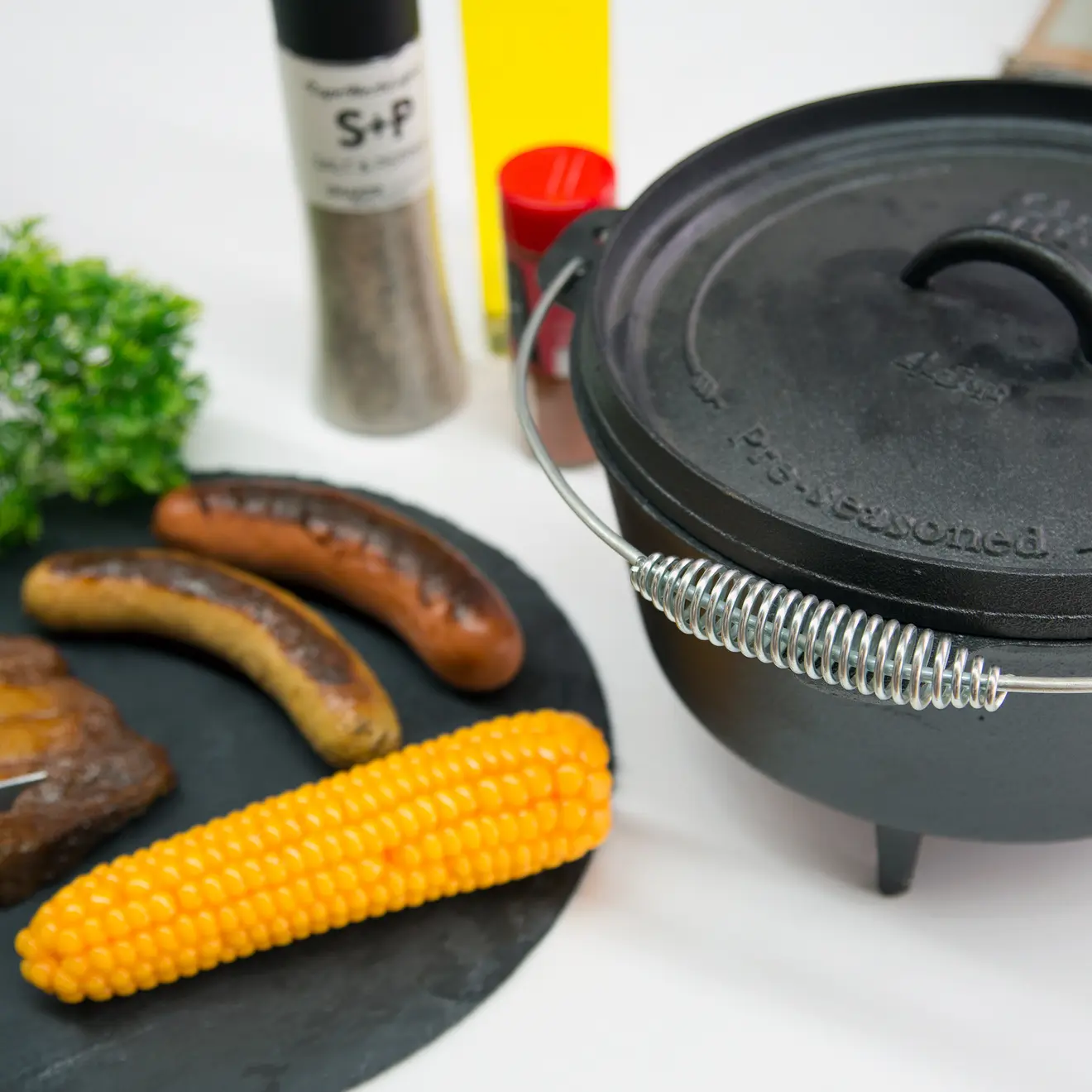 Dutch Oven mit Mais und Würstchen daneben