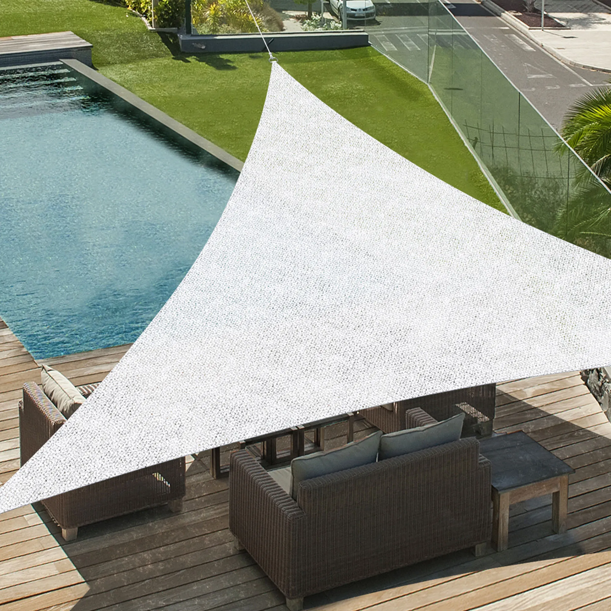 Telo da sole triangolare sopra la terrazza con mobili e piscina sullo sfondo